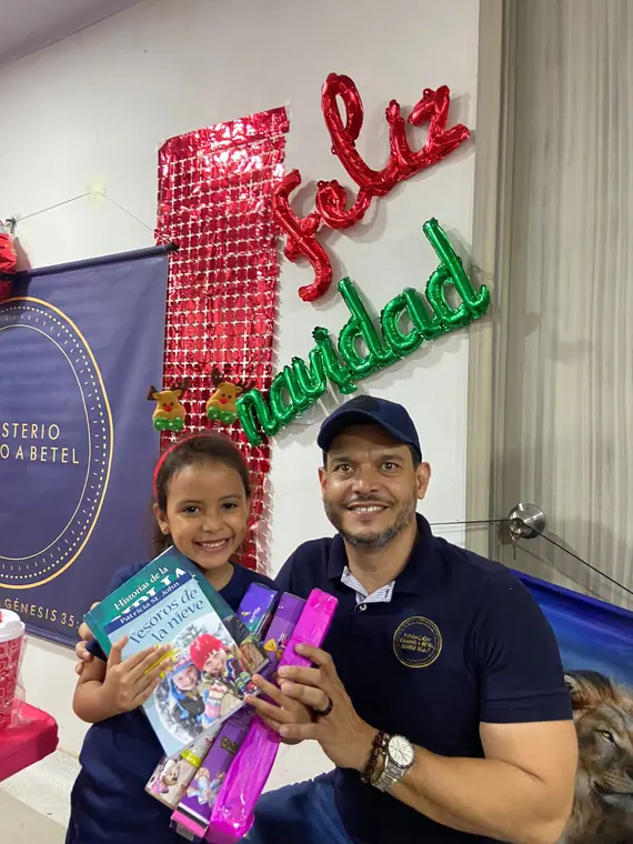 Niña y voluntario con sus regalos de Navidad