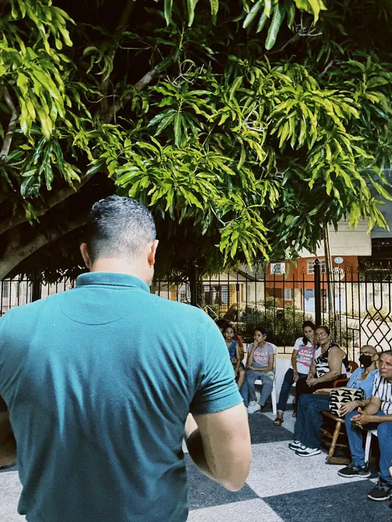 Voluntario frente a familias reunidas bajo los árboles