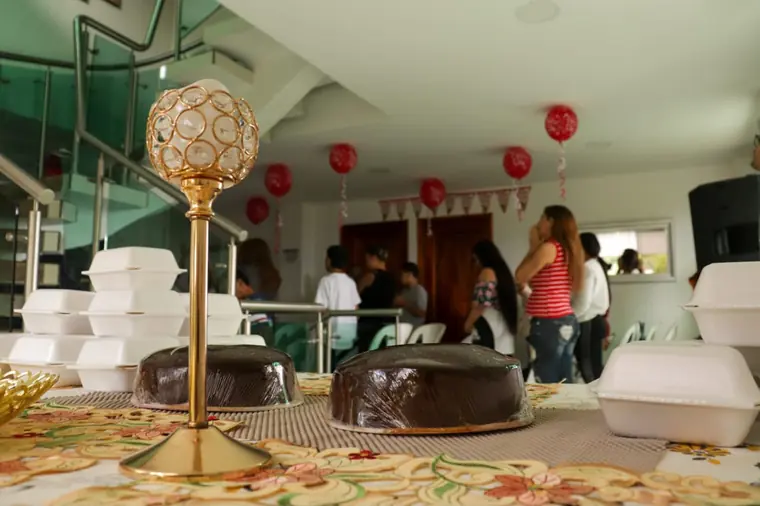 Mesa con tortas y decoración dorada, con globos rojos al fondo